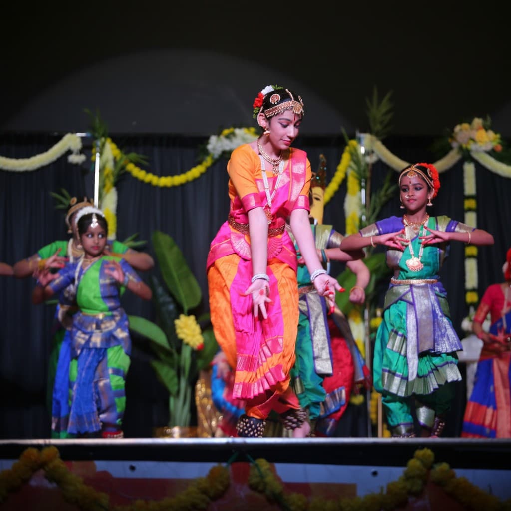 Children performing classical dance in colourful traditional attire on a decorated stage